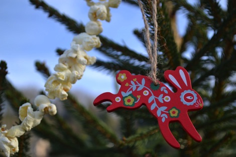 Red wooden rabbit decoration on a real Christmas tree with popcorn garland